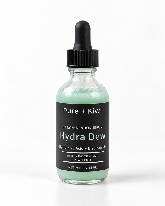 A 2 oz glass dropper bottle of Pure + Kiwi Hydra Dew Daily Hydration Serum, featuring a light mint green liquid inside a clear glass bottle with a black dropper cap and black label.